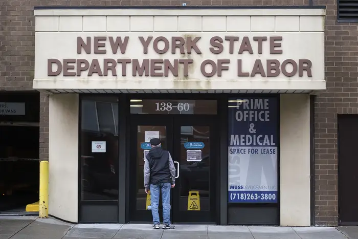 A person reads a sign on the door of an office of the New York State Department of Labor closed due to the COVID-19 pandemic in New York.